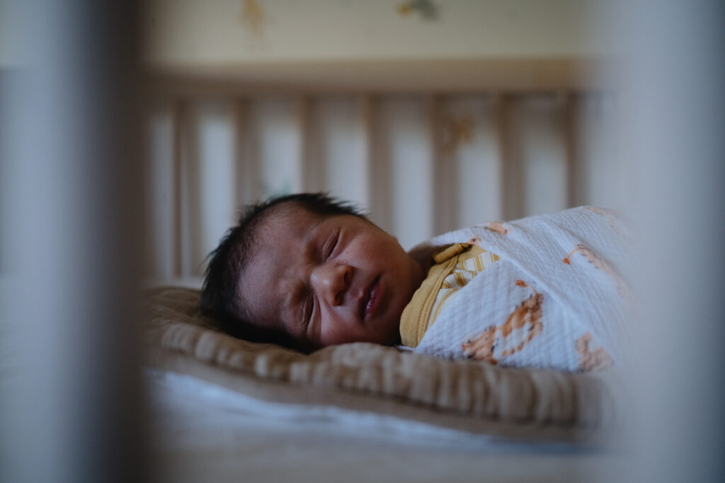 A newborn baby asleep in his crib. 