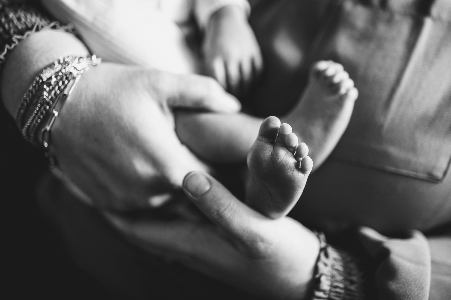 Black & white image of little newborn feet in mom's hands.