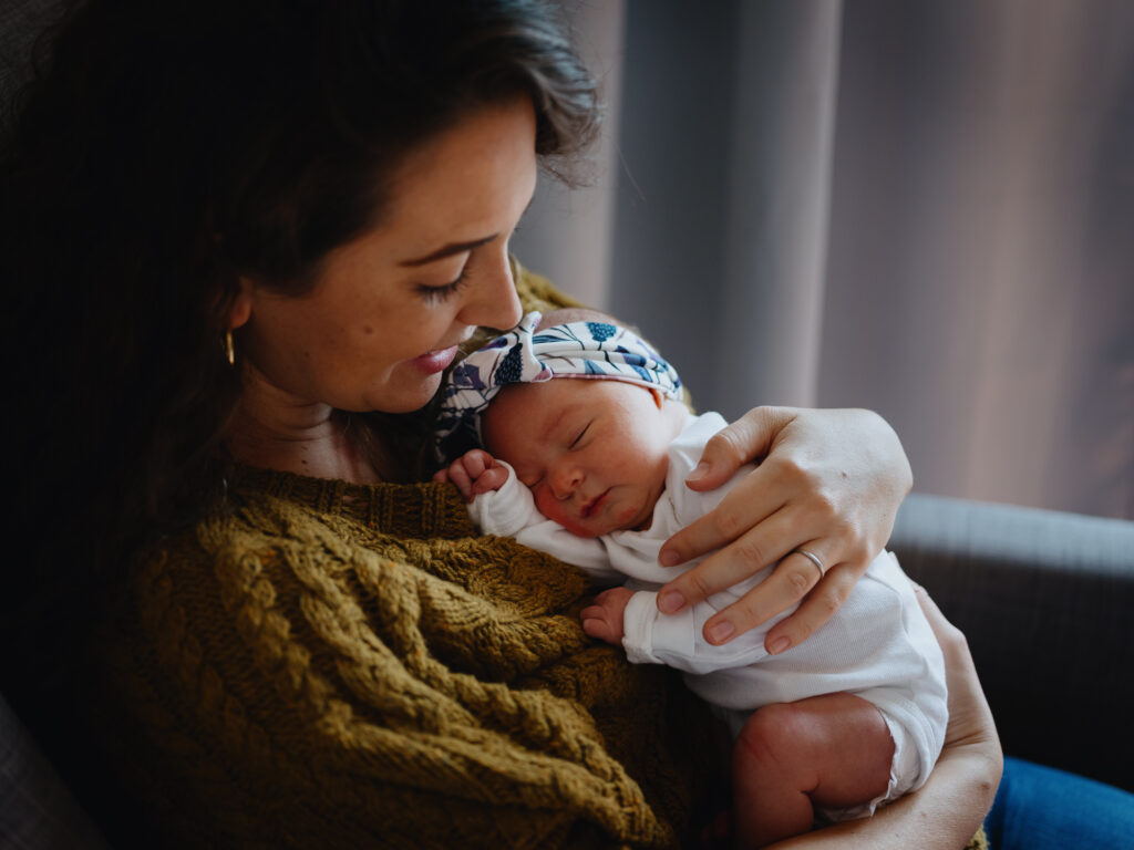 Intimate portrait of a mother and her newborn baby nestled in her arms. 