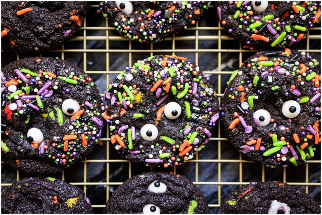 Halloween monster cookies made with black cocoa powder, halloween-themed sprinkles, and googly eyes.
