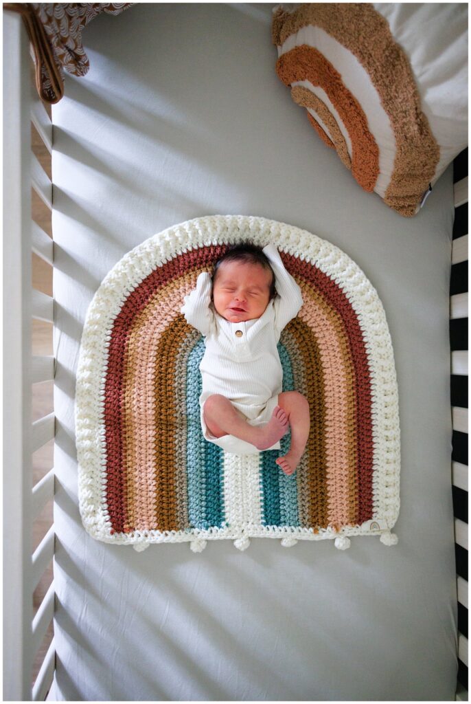 Overhead crib shot of a newborn baby boy in his rainbow blanket. 