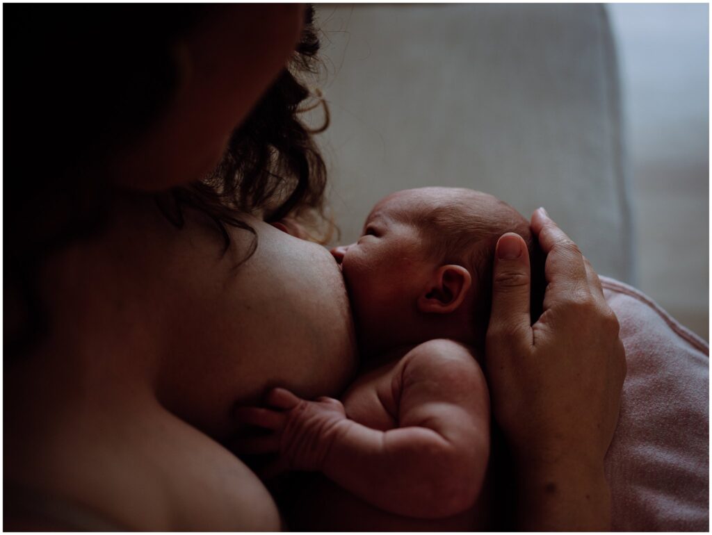Mother and newborn daughter breastfeeding skin-to-skin.