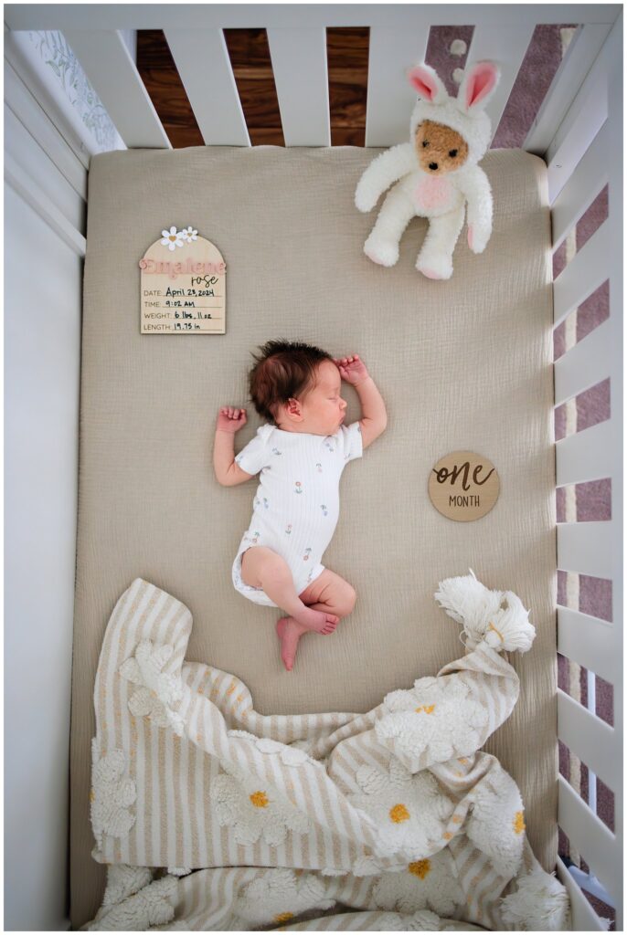 Overhead crib shot of newborn baby girl with milestone blocks. 