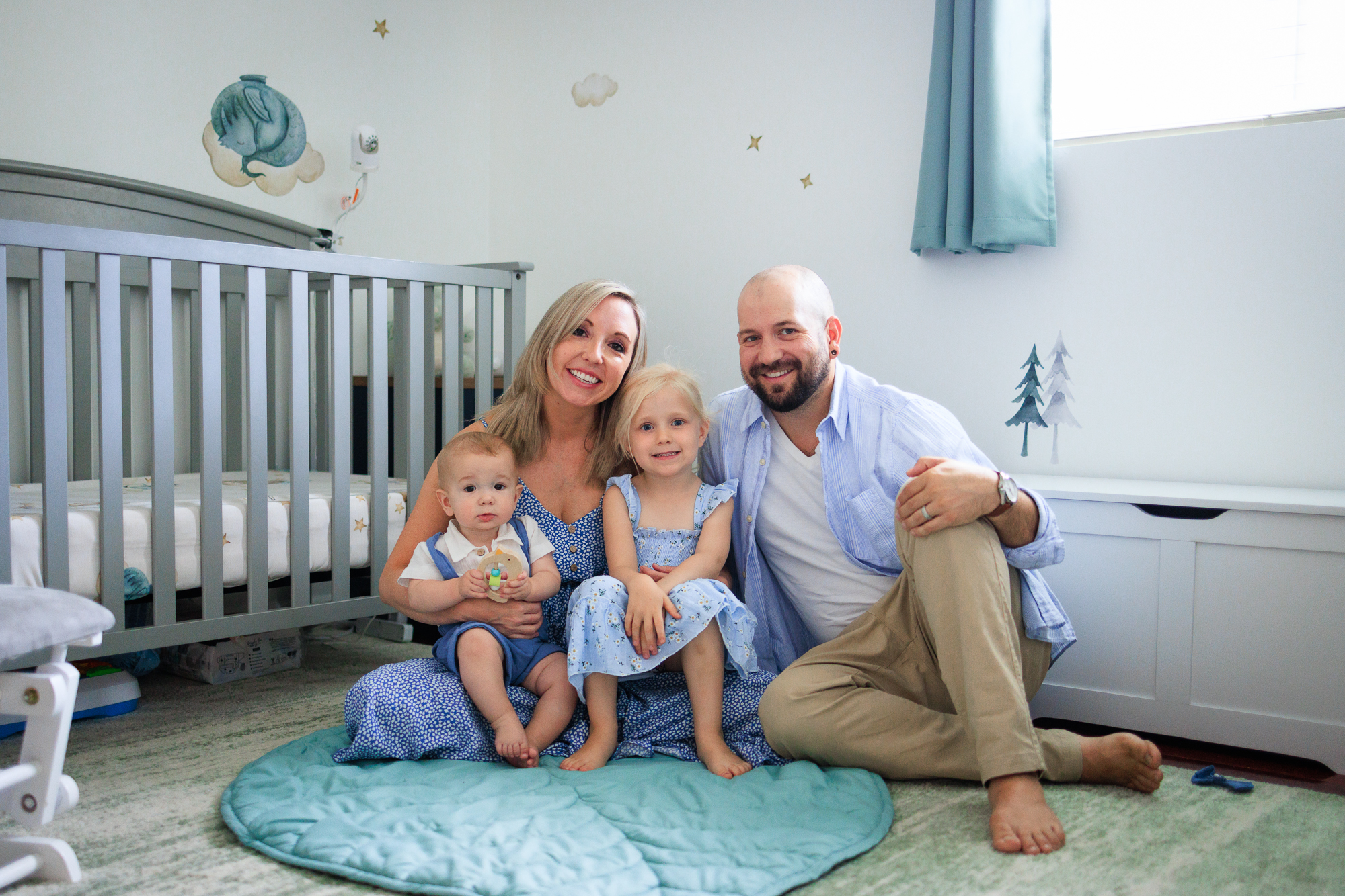 Family photo with mom, dad, toddler girl, and baby boy taken in the nursery.